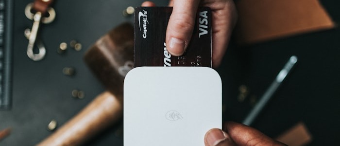 A customer handing a credit card over a card reader