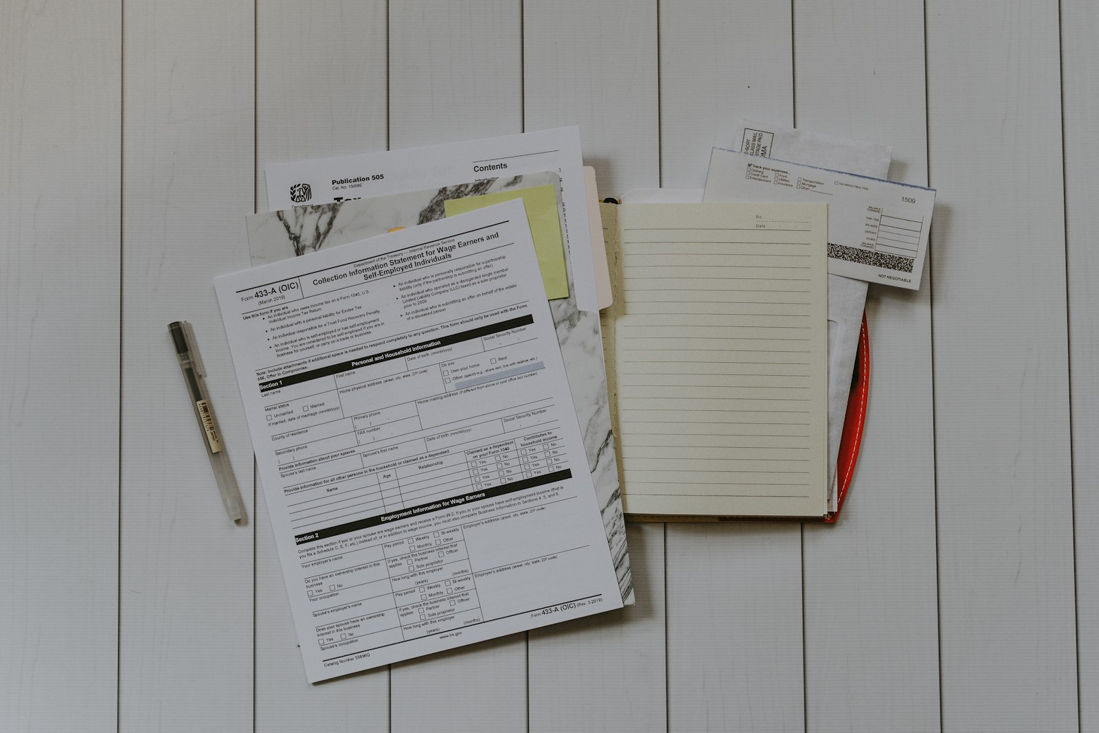 Official forms, envelopes and a notebook laid out on a desk